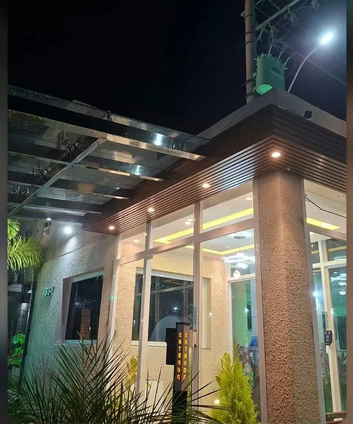 Fachada iluminada à noite com estrutura metálica e cobertura de vidro